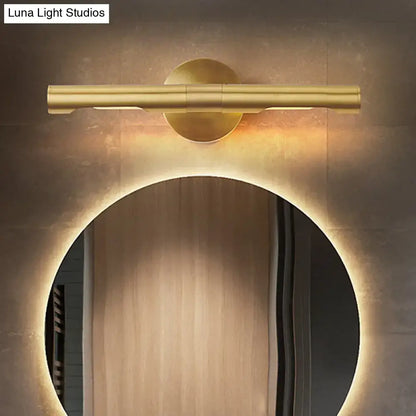 Modern brass tube vanity light featuring a gold-toned cylindrical tube and circular base emitting warm ambient light