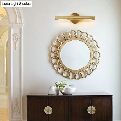 Modern brass tube vanity light featuring a gold-toned circular mirror with a decorative chain-link frame for bathroom use