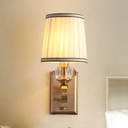 Elegant black brass wall lamp with direct wired electric feature, pleated cream shade, and crystal accents for bedroom use
