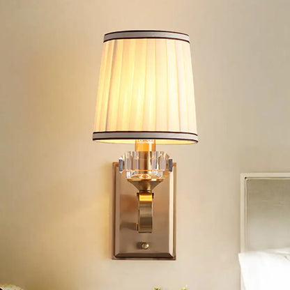 Elegant black brass wall lamp with direct wired electric feature, pleated cream shade, and crystal accents for bedroom use