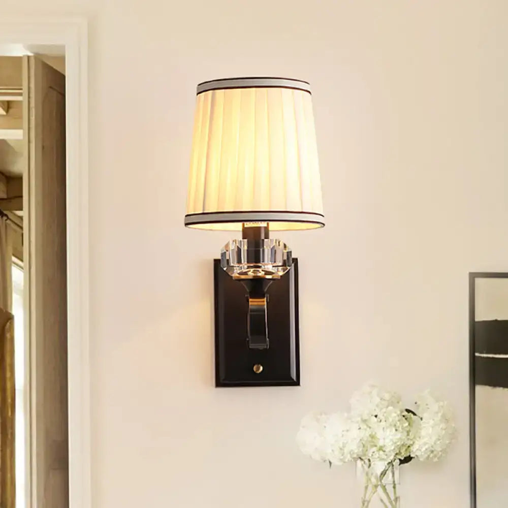Elegant black brass wall lamp with direct wired electric installation featuring a pleated cream shade and crystal accents