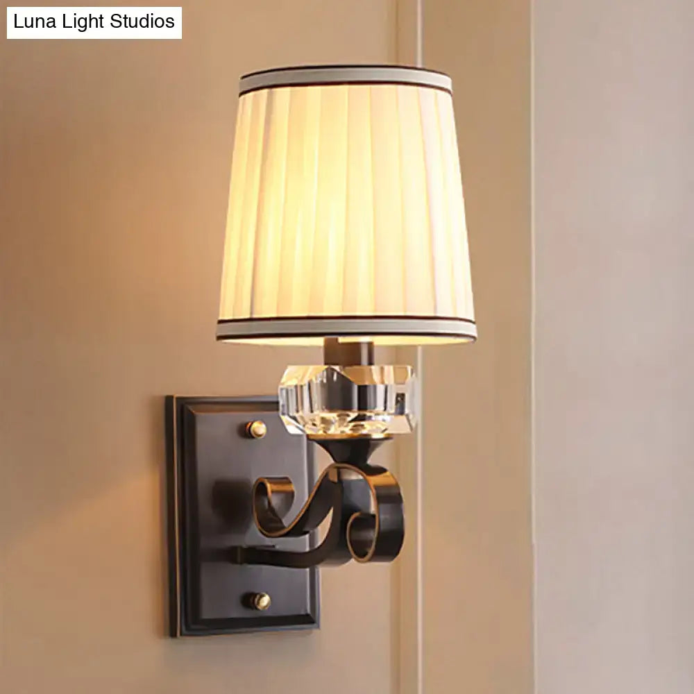 Elegant black brass wall lamp with direct wired electric installation featuring a cream pleated shade and crystal accent