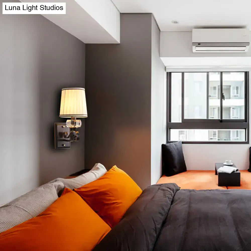 Orange velvet throw pillows on a bed with a modern black brass wall lamp direct wired electric bedroom sconce