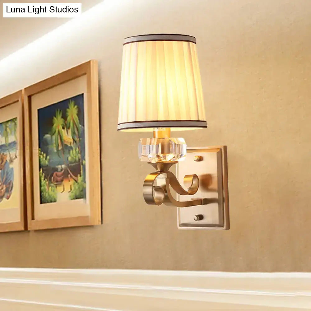 Modern brass wall lamp with direct wired electric installation features a beige pleated shade with black brass trim