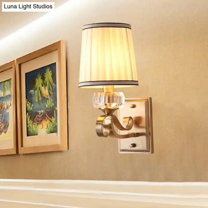 Modern brass wall lamp with direct wired electric installation features a beige pleated shade with black brass trim