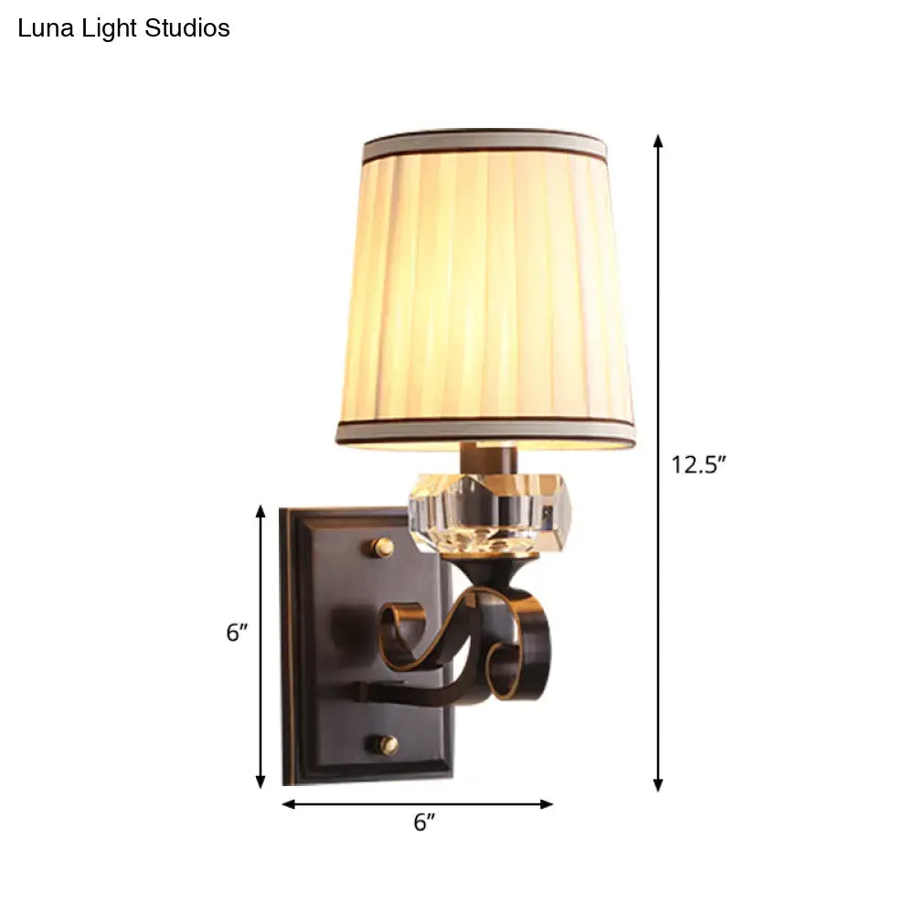 Modern black brass wall lamp with direct wired electric fitting features a warm pleated shade and ornate bronze sconce
