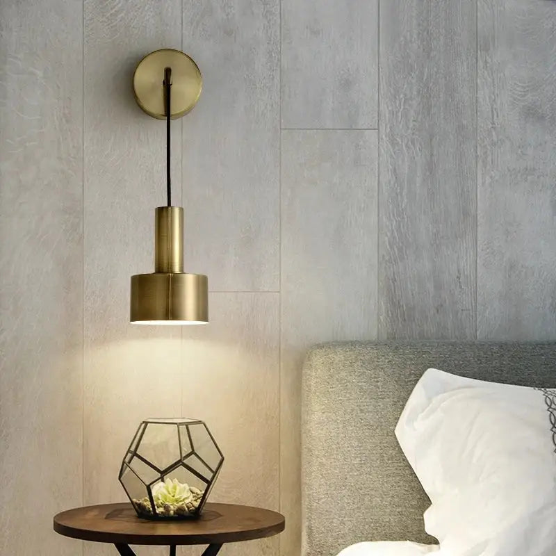 Modern brass wall lamp with a cylindrical brass-finished pendant design mounted on a circular wall sconce decorbites brass wall