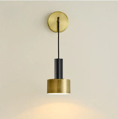 Modern brass wall lamp with black cylindrical shade and circular brass mount for minimalist living room decorbites brass wall lamp