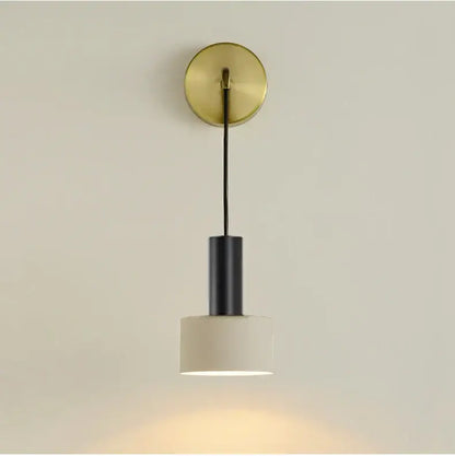 Minimalist wall lamp with brushed brass base, black cylindrical stem, and off-white ceramic shade for modern decorbites brass wall lamp