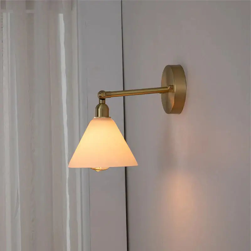 Modern brass wall lamp with warm-toned brass and frosted conical clear glass shade for bedroom reading decorbites clear glass