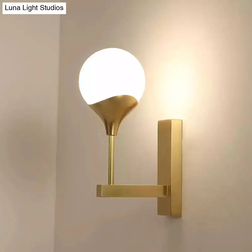 Modern brass wall lamp with gold-toned metal arm and frosted glass shade wall light for bedroom use