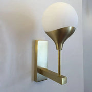 Modern brass wall lamp with a cream glass shade featuring a gold-toned metal base for bedroom wall light use