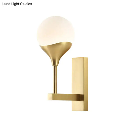 Modern brass wall lamp with gold-toned geometric metal base and cream glass shade for bedroom wall light