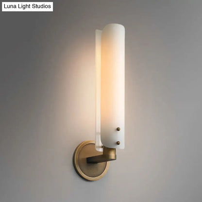 Modern brass wall lamp with frosted opal glass shade and cylindrical design for bedroom sconce lighting