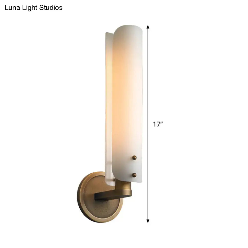 A sleek 17-inch modern brass wall lamp with a warm-toned opal glass shade for bedroom use