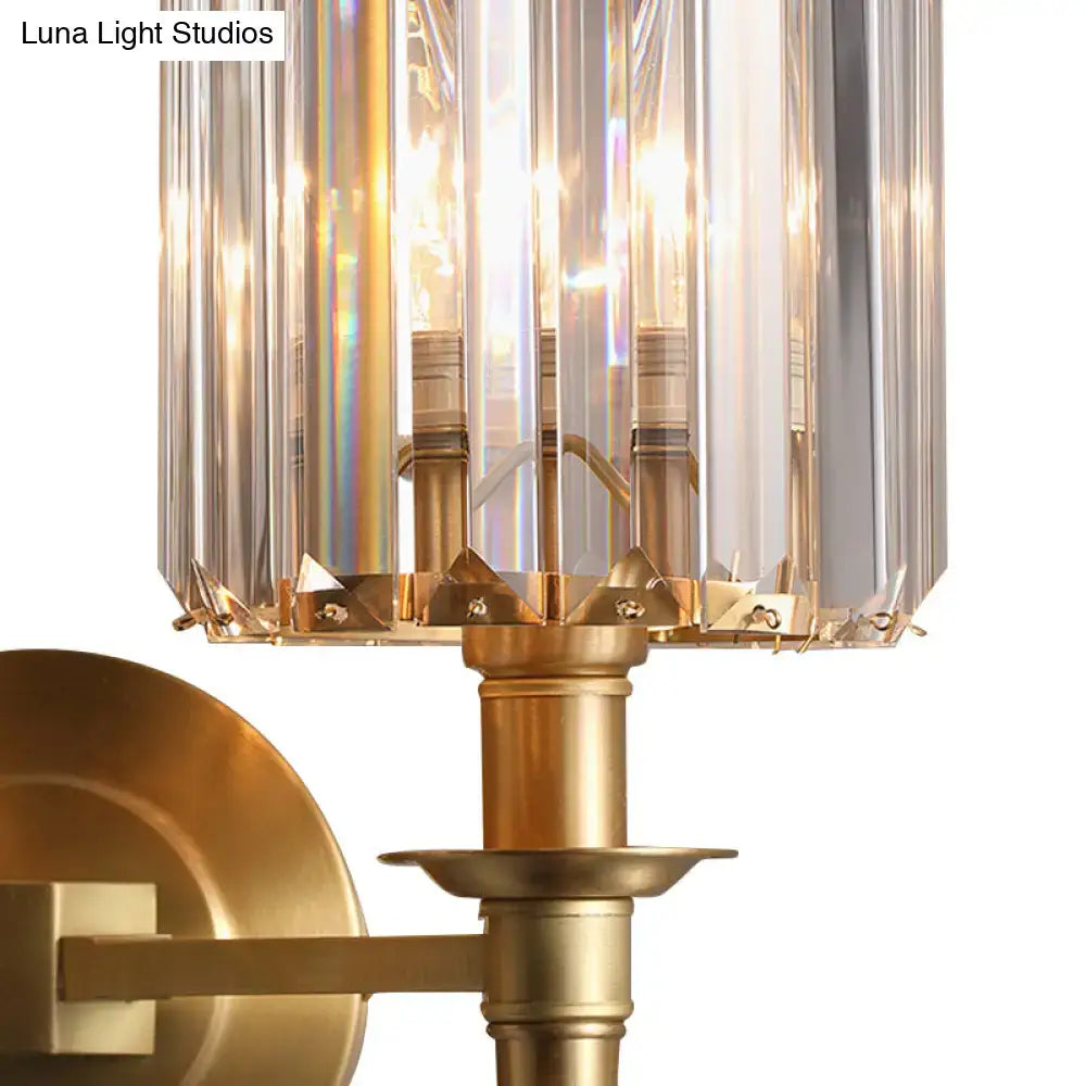 Modern brass wall light sconce with a gold-toned crystal shade casting a warm sparkling glow for bedroom use