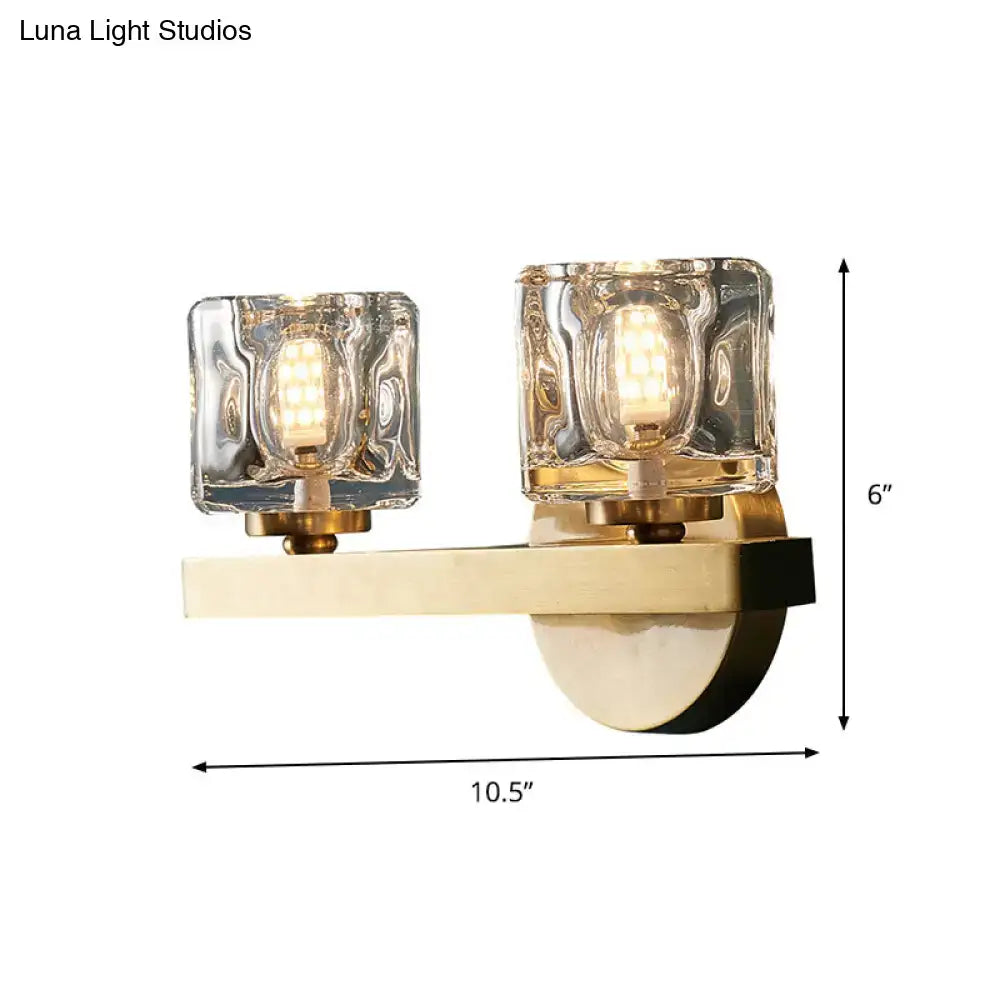 Modern brass wall light with clear crystal block and two textured glass shades housing led bulbs for living room use