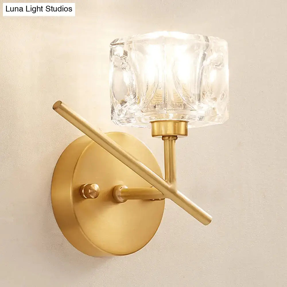 Modern brass wall light with gold-toned finish and a clear crystal shade for elegant bedroom sconce lighting