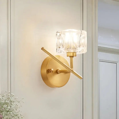 Modern brass wall light with gold-toned finish and clear crystal shade for elegant bedroom sconce lighting