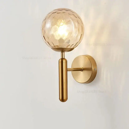 Modern brass wall lights featuring a gold-toned wall sconce with a textured amber-hued decorbites glass ball globe for living room