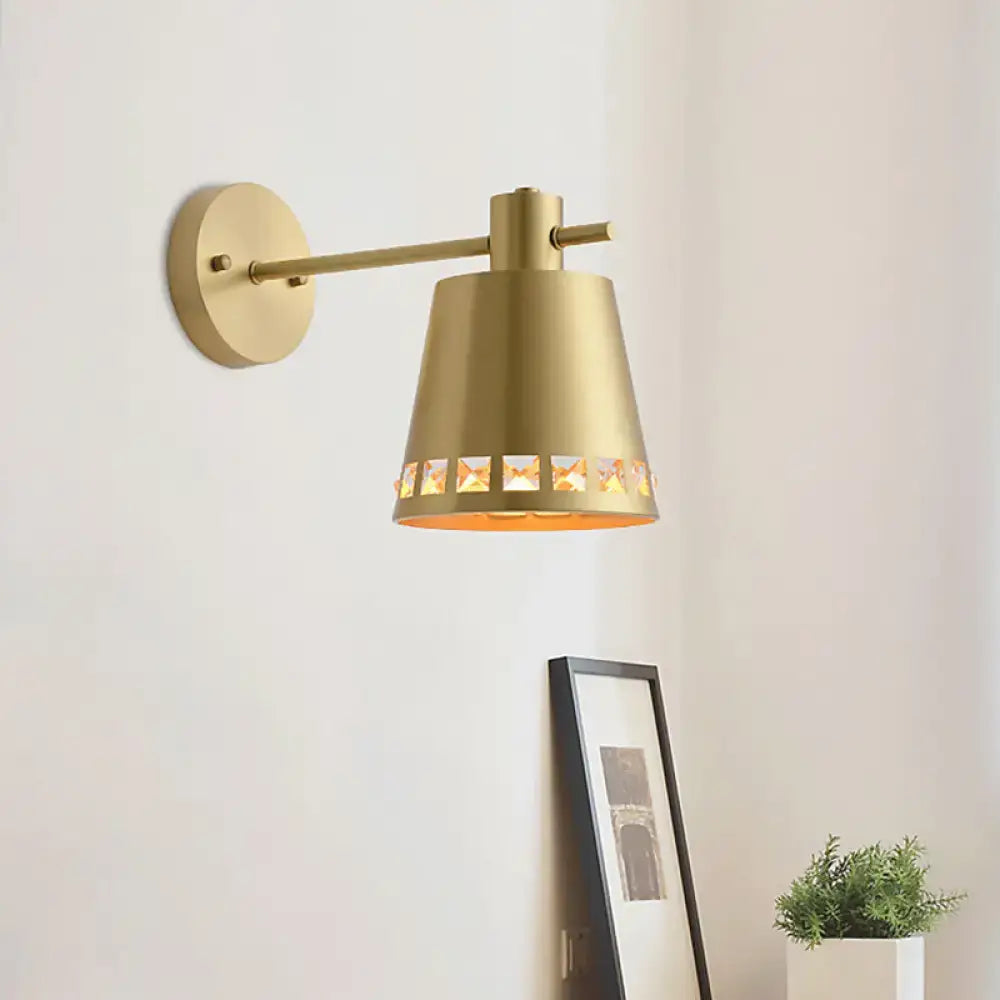 Modern brass wall mount light with clear crystal accent and gold-toned conical shade featuring decorative cut-out patterns