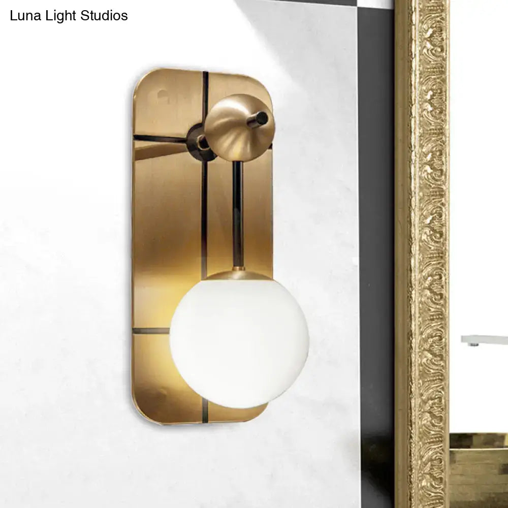 Modern brass wall sconce with opal glass spherical shade and minimalist geometric design for direct wired installation