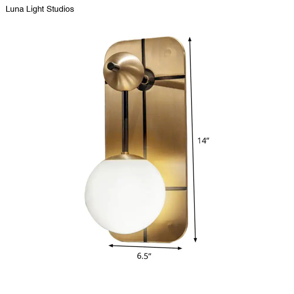 Modern brass wall sconce with opal glass spherical shade and sleek rectangular direct wired backplate for bedroom lighting