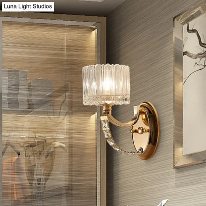 Elegant modern brass wall sconce with gold tone and faceted clear glass shade featuring decorative crystal accents