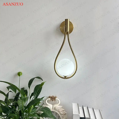 Modern brass wall sconce with gold-toned teardrop design and frosted glass globe for living room decorbites brass wall sconce