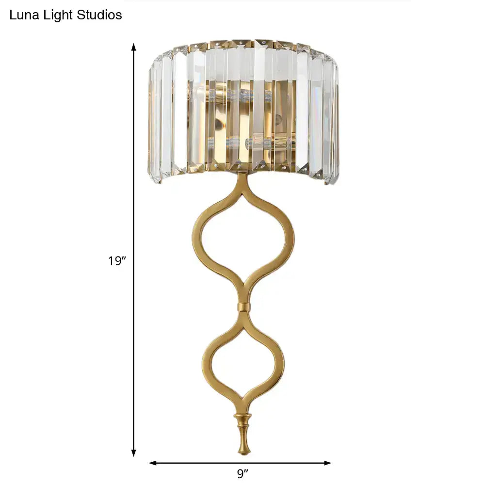 Gold-toned modern brass wall sconce with crystal rectangle shade and ornate curved metal base great choice for wall mount lighting