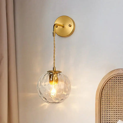 Modern brass water glass shade sconce with gold-toned wall mount textured clear glass globe and twisted cord for bedroom wall light