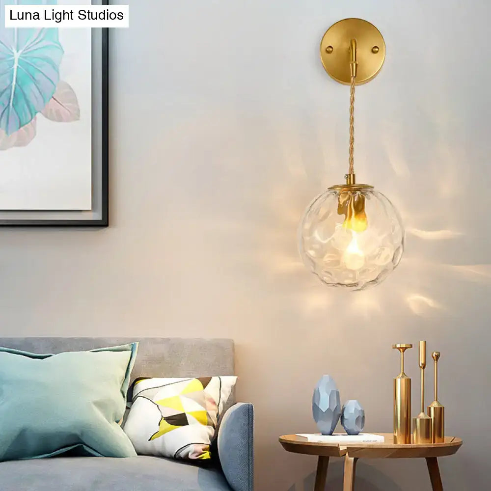 Modern brass water glass shade sconce with gold-toned finish textured clear glass globe and braided cord for bedroom wall light