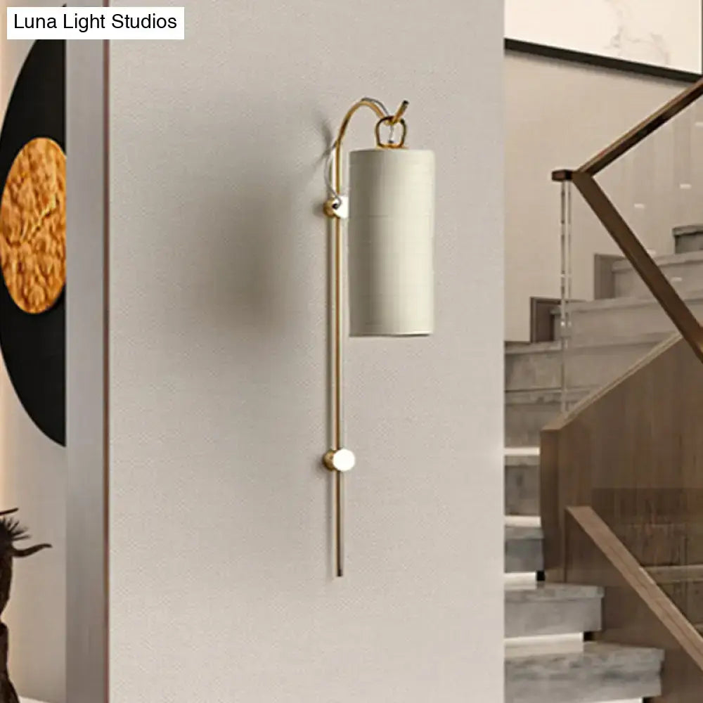 A modern brass and white wall sconce with a gold metal frame and off-white fabric shade for direct wired electric 220v-240v use
