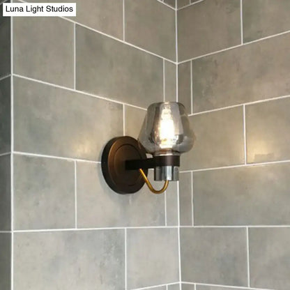A modern bronze and brass smoke gray wall lamp with a brushed brass sconce and mercury glass shade for porch lighting