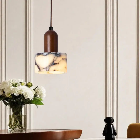 A modern brown and cream marble pendant light with a warm cylindrical stem for dining room lighting