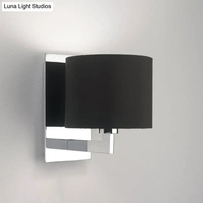 Modern brown fabric wall mount sconce with a sleek chrome metal frame and matte black cylindrical shade for bedroom lighting