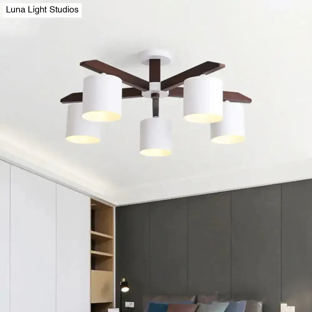 Modern ceiling mount chandelier with five white cylindrical shades and dark wood arms for living room lighting