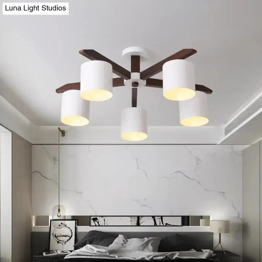 Modern brown and white ceiling mount chandelier with five white cylindrical shades and dark wood arms for living room use