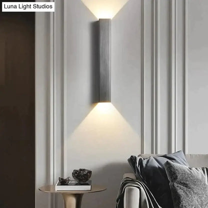 Modern brushed aluminum rectangular wall sconce with sleek metallic body emitting warm ambient bedroom light