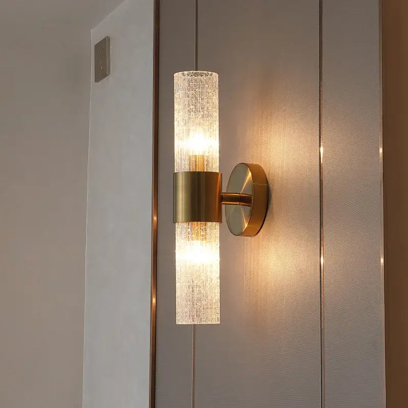 A modern brushed brass crystal wall lamp with a textured translucent glass cylinder for bedroom decorbites wall lamp