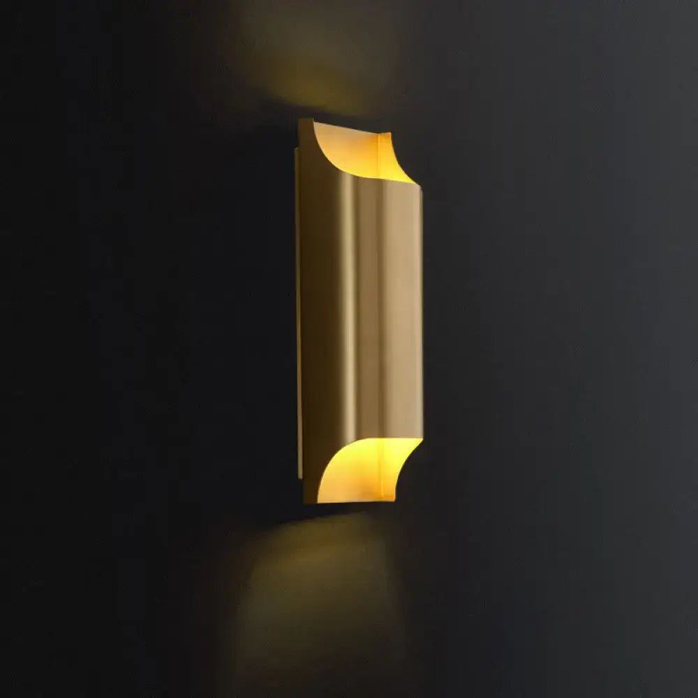 Modern brushed brass flush wall sconce with a curved sculptural design emitting warm yellow light for stairwell lighting