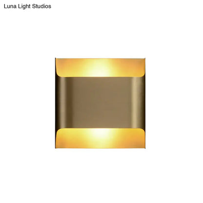 Modern brushed brass flush wall sconce with warm amber light from top and bottom curved panels for stairwell use