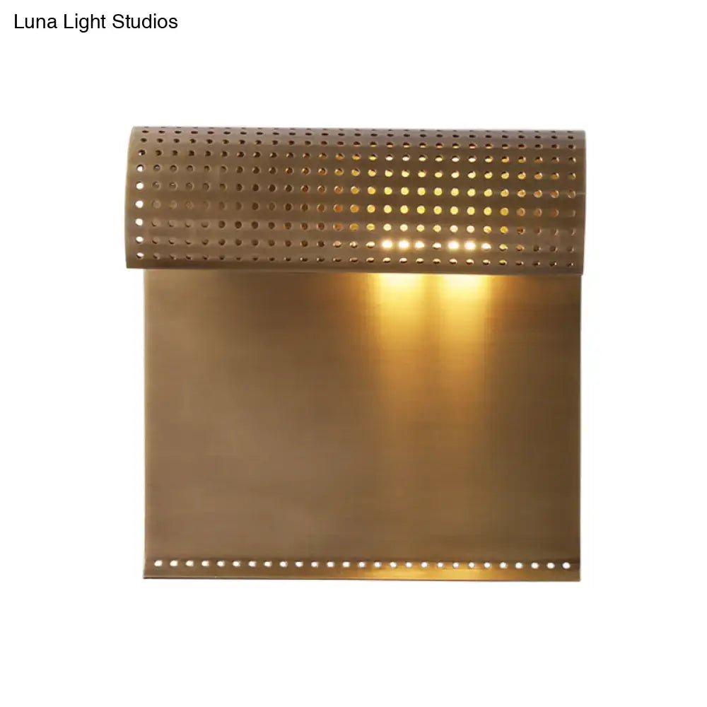 Modern brass scrolled wall sconce with perforated edges emitting warm light for bedroom wall mounted lighting