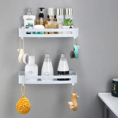 White plastic two-tier wall-mounted bathroom corner shelf with hanging hooks holding bath items by decorbites brushed gold aluminum