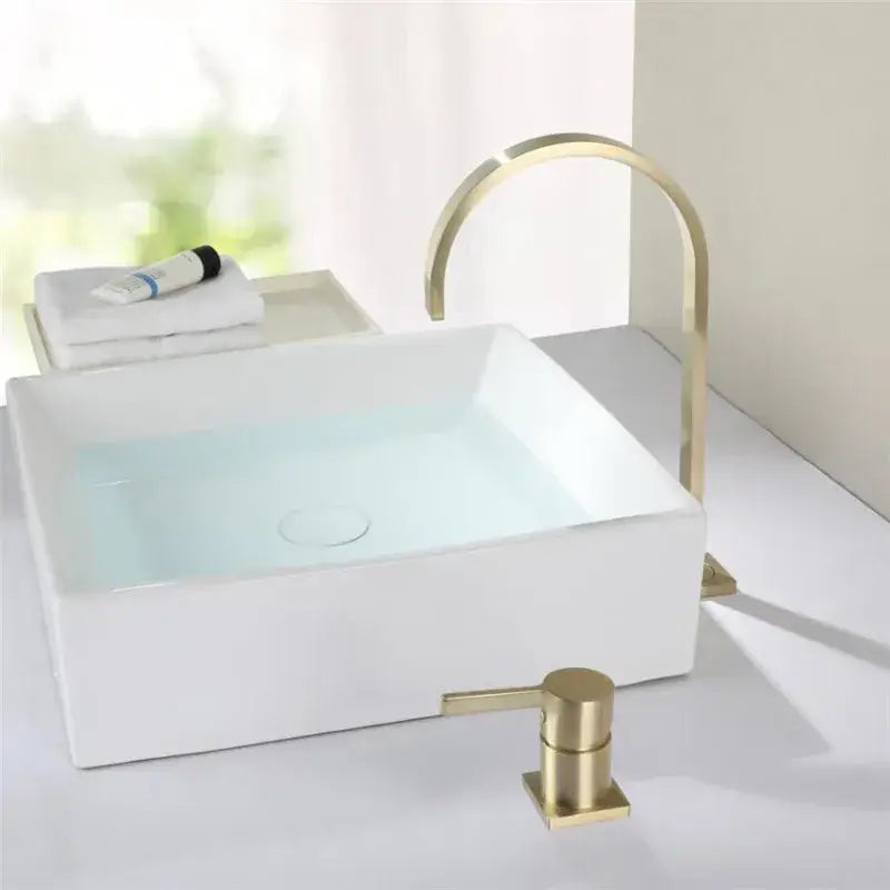 Modern brushed gold basin faucet with sleek curved spout and matching dispenser paired with white vessel sink decorbites brushed gold