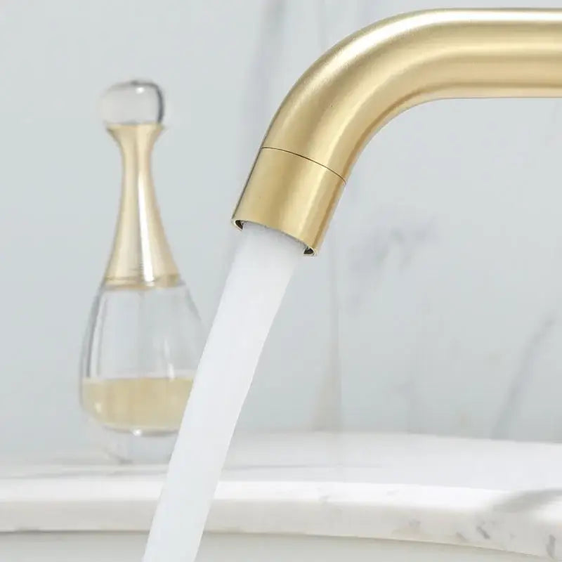 Modern brushed gold basin faucet with sleek curved design and flowing water stream from decorbites brushed gold collection