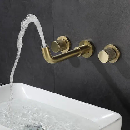 Brass-finished brushed gold basin faucet with textured knobs and curved spout flowing water into white sink decorbites brushed gold