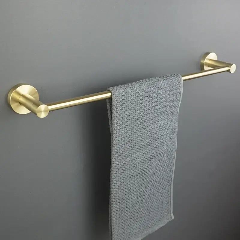 A sleek brushed gold bath hardware set towel rack with matte finish holds a neatly draped gray textured towel