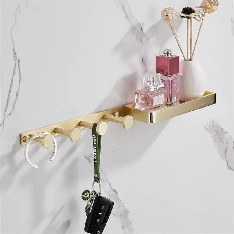 Modern brushed gold metal bathroom hardware set with wall-mounted shelf, circular hooks, and decorative perfume holders