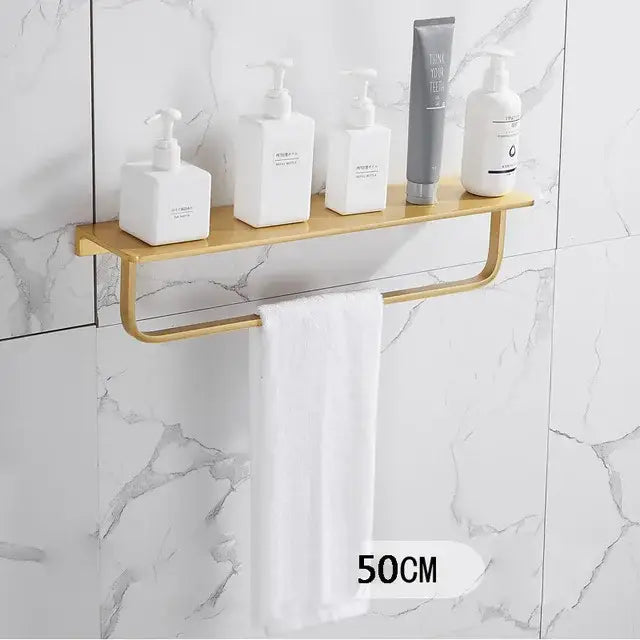 Modern brushed gold bathroom set with metal shelf and integrated towel bar holding white and gray toiletry bottles decorbites brushed gold